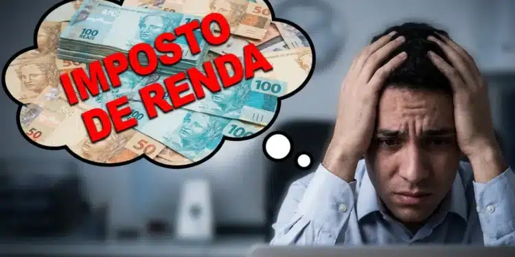 Homem preocupado segurando a cabeça diante do computador pensando no Imposto de Renda com notas de dinheiro ao fundo