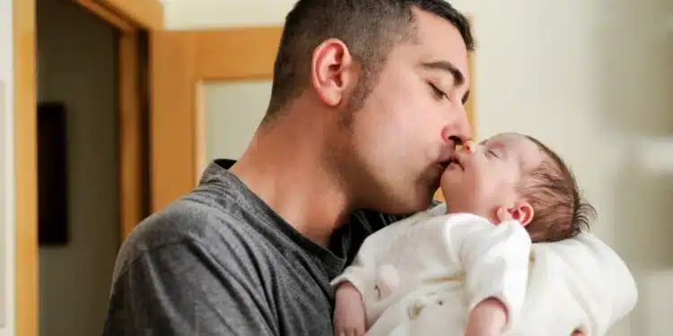 Pai beijando seu recém-nascido em momento de carinho, simbolizando o impacto da ampliação da licença-paternidade.