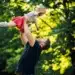 Pai levantando filha no parque, simbolizando o apoio e a importância da licença-paternidade ampliada.