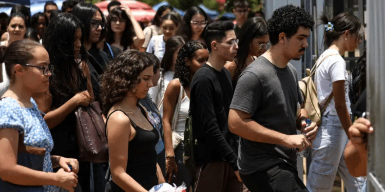 Grupo de jovens segurando garrafas de água, entrando em portão de escola