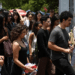 Grupo de jovens segurando garrafas de água, entrando em portão de escola