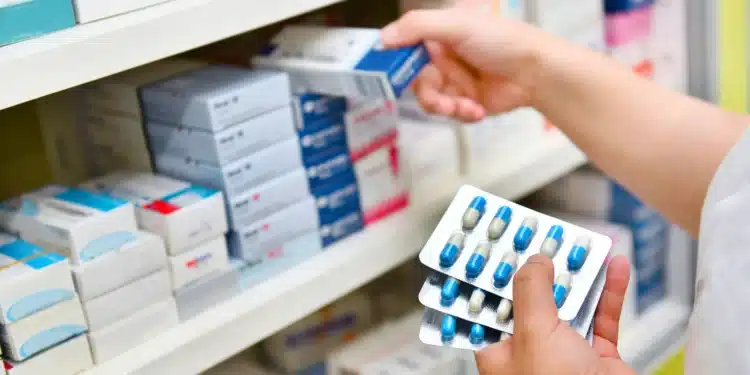 Farmacêutico selecionando medicamentos em uma prateleira, com destaque para caixas e cartuchos de remédios, ilustrando o contexto de possíveis reajustes de preços no Brasil.