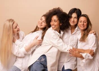 Cinco mulheres sorrindo e abraçadas representam união, diversidade e fortalecimento feminino na data de 8 de março.