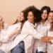 Cinco mulheres sorrindo e abraçadas representam união, diversidade e fortalecimento feminino na data de 8 de março.