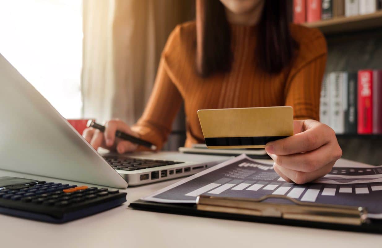 Pessoa consultando fatura e utilizando cartão de crédito enquanto organiza pagamentos e negocia dívidas com instituições financeiras.