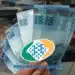 Notas de reais e logo do INSS representando o pagamento de 50% a mais no depósito de abril