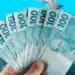 Notas de R$100 do Brasil com valores destacados, relacionadas aos pagamentos do INSS para beneficiários com finais 3, 4, 5, 8, 9 e 0, entre 4 e 6 de março.