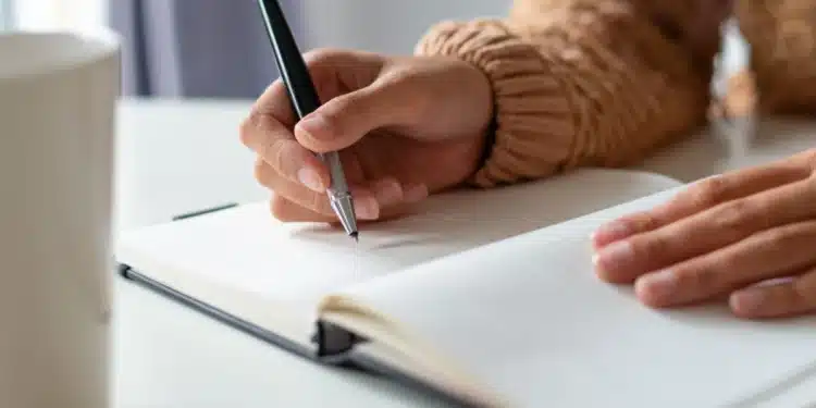 Pessoa escrevendo em um caderno durante estudo sobre palavras da língua portuguesa que não possuem forma no plural