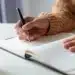 Pessoa escrevendo em um caderno durante estudo sobre palavras da língua portuguesa que não possuem forma no plural
