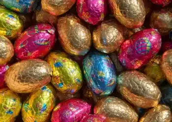 Ovos de Páscoa coloridos embalados em papel metalizado representando a chegada da Páscoa 2026 no calendário.