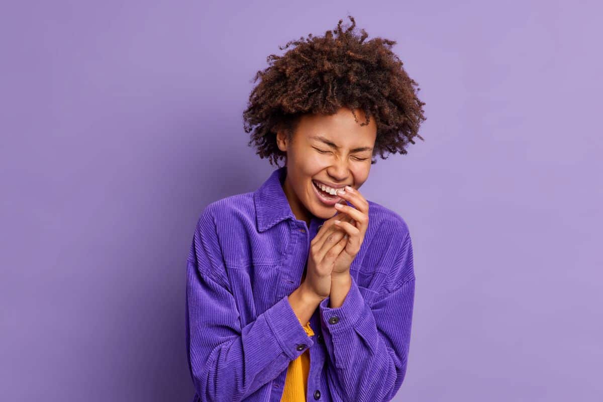 Mulher sorrindo com expressão de diversão representando o clima de brincadeiras do Dia da Mentira.