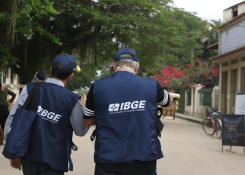 Dois agentes do IBGE uniformizados de costas caminhando em área urbana — concurso IBGE recenseador 27 mil vagas 2026