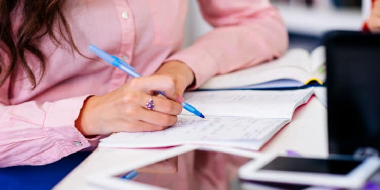 Candidata estudando e anotando em caderno para o processo seletivo da Prefeitura de Chapadão do Céu GO com salários de até R$ 3.156 para Agente de Saúde