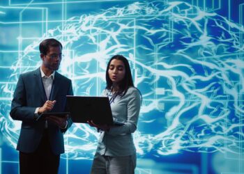 Profissionais de tecnologia analisando sistema de inteligência artificial em ambiente digital com visualização de rede neural.