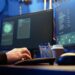 Profissional de tecnologia trabalhando em um ambiente de escritório moderno com dois monitores, digitando código, com um copo de café ao lado, refletindo as tendências das profissões digitais em 2026 no Brasil.