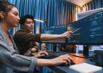 Profissionais analisando dados em computadores enquanto utilizam ferramentas de inteligência artificial para programação, marketing e análise financeira.