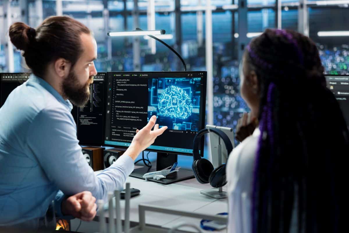 Especialista em tecnologia analisando códigos e testando comandos de inteligência artificial em estação de trabalho com vários monitores.