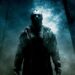 Figura sombria do personagem Jason Voorhees, de Sexta-Feira 13, usando sua icônica máscara de hóquei. Ele está em pé em uma floresta nebulosa e escura à noite, iluminada por uma luz azulada vinda de trás das árvores.