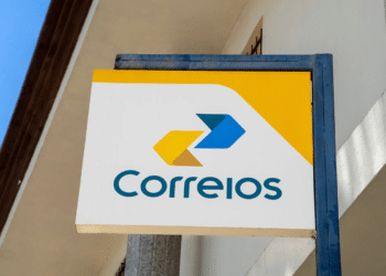 Placa dos Correios com logotipo amarelo e azul fixada na fachada de prédio
