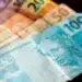 Notas de dinheiro em formato de 13º salário do INSS, destacando valores de R$ 20, R$ 50 e R$ 100, para ilustrar o pagamento da primeira parcela do 13º salário de 2026.