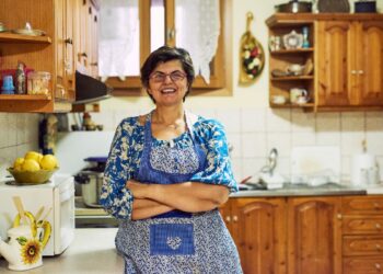 Dona de casa na cozinha representando mulheres que precisam contribuir ao INSS para garantir aposentadoria em 2026.