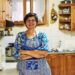 Dona de casa na cozinha representando mulheres que precisam contribuir ao INSS para garantir aposentadoria em 2026.