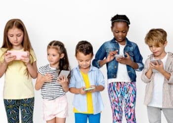 Crianças utilizando smartphones em contexto de uso intenso de redes sociais e tecnologia digital.