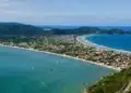 Vista panorâmica da cidade de Bombinhas, no litoral catarinense, com praias deslumbrantes e morros ao fundo, destacando o paraíso natural da região.