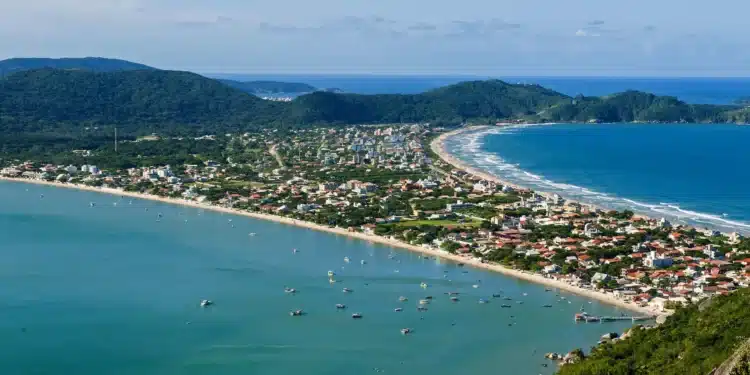 Vista panorâmica da cidade de Bombinhas, no litoral catarinense, com praias deslumbrantes e morros ao fundo, destacando o paraíso natural da região.