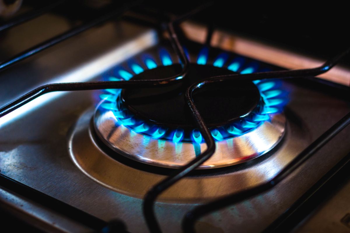 Chama azul acesa em fogão doméstico representando uso de gás de cozinha.