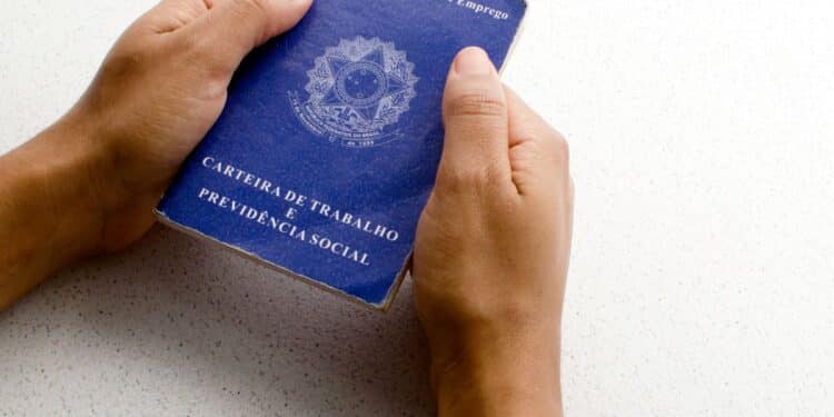 Mãos segurando uma carteira de trabalho.