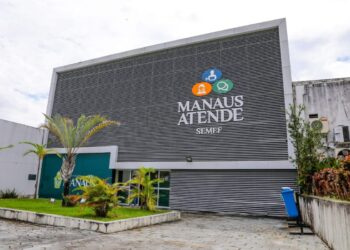 Fachada do prédio da SEMEF Manaus Atende, com estrutura cinza moderna e logomarca colorida, representando a sede da Secretaria Municipal de Finanças de Manaus.