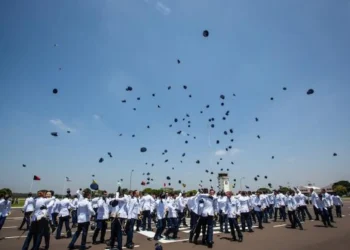 Formatura de cadetes do Comando da Aeronáutica com chapéus sendo lançados ao ar, simbolizando o fim do curso e o início da jornada como oficiais..