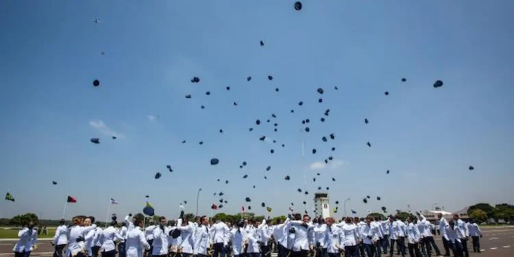 Formatura de cadetes do Comando da Aeronáutica com chapéus sendo lançados ao ar, simbolizando o fim do curso e o início da jornada como oficiais..