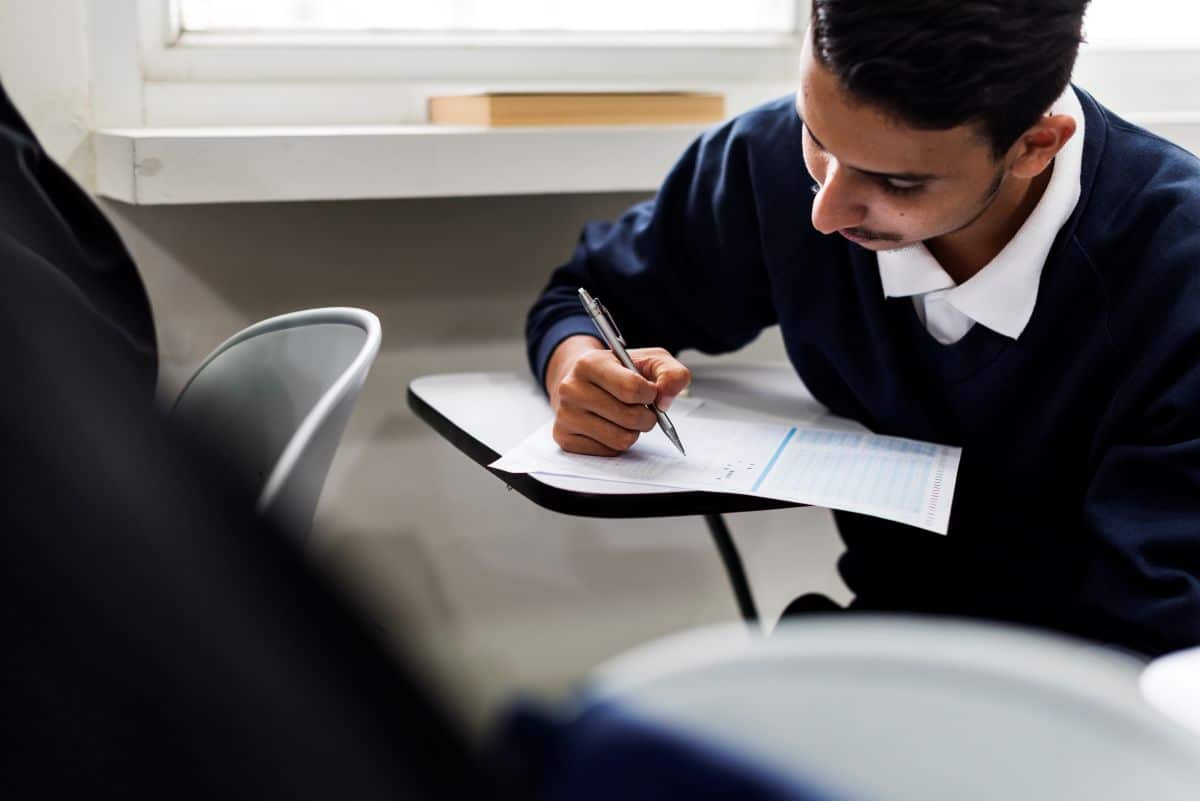 Estudante concentrado fazendo prova em sala de aula.