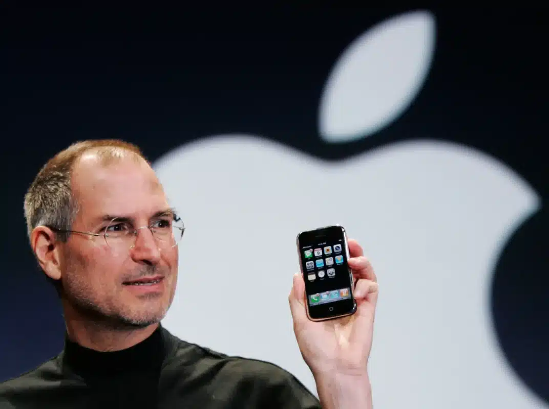 Steve Jobs apresenta o primeiro iPhone, simbolizando a revolução da Apple na tecnologia de smartphones