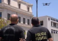 Dois agentes da Polícia Federal observando um drone sobrevoando a sede da corporação, representando a inovação no concurso e nomeação de excedentes.