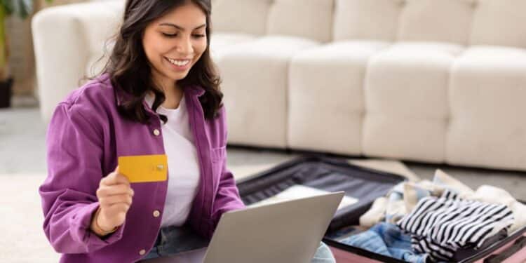Mulher sorrindo enquanto planeja sua viagem usando um laptop e segurando um cartão de crédito, destacando a facilidade da busca por passagens aéreas com ferramentas como o Skyscanner integrado ao ChatGPT.