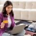 Mulher sorrindo enquanto planeja sua viagem usando um laptop e segurando um cartão de crédito, destacando a facilidade da busca por passagens aéreas com ferramentas como o Skyscanner integrado ao ChatGPT.