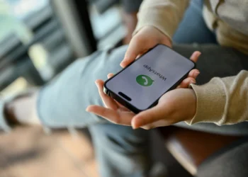 Pessoa segurando smartphone com WhatsApp aberto, ilustrando como evitar mensagens de listas de transmissão.