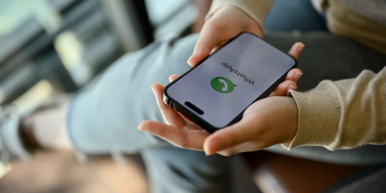 Pessoa segurando smartphone com WhatsApp aberto, ilustrando como evitar mensagens de listas de transmissão.
