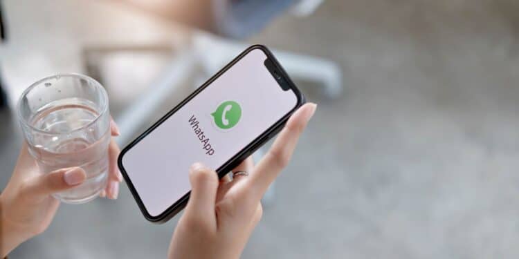 Pessoa segurando smartphone com tela inicial do WhatsApp exibida, ilustrando mudanças de personalização no aplicativo.