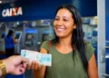 Mulher recebendo dinheiro em frente à Caixa, em referência ao pagamento do Abono Salarial para os nascidos em novembro e dezembro.