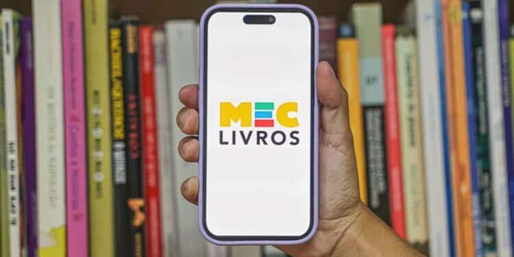 MEC Livros biblioteca digital gratuita - mão segurando smartphone com logo MEC Livros em frente a estante de livros