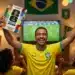 Álbum da Copa do Mundo 2026 em pré-venda, sendo segurado por torcedor brasileiro que comemora enquanto assiste a um jogo de futebol.