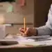 Mulher escrevendo em um caderno durante o trabalho, destacando a habilidade rara de anotar no papel em vez de usar o celular.