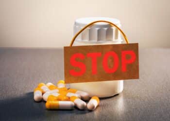 Medicamentos e cápsulas com placa de “stop”, representando proibição de produtos irregulares pela Anvisa.