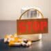 Medicamentos e cápsulas com placa de “stop”, representando proibição de produtos irregulares pela Anvisa.