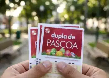 Pessoa segurando bilhetes do sorteio Dupla de Páscoa 2026, com fundo desfocado de um parque ao ar livre.