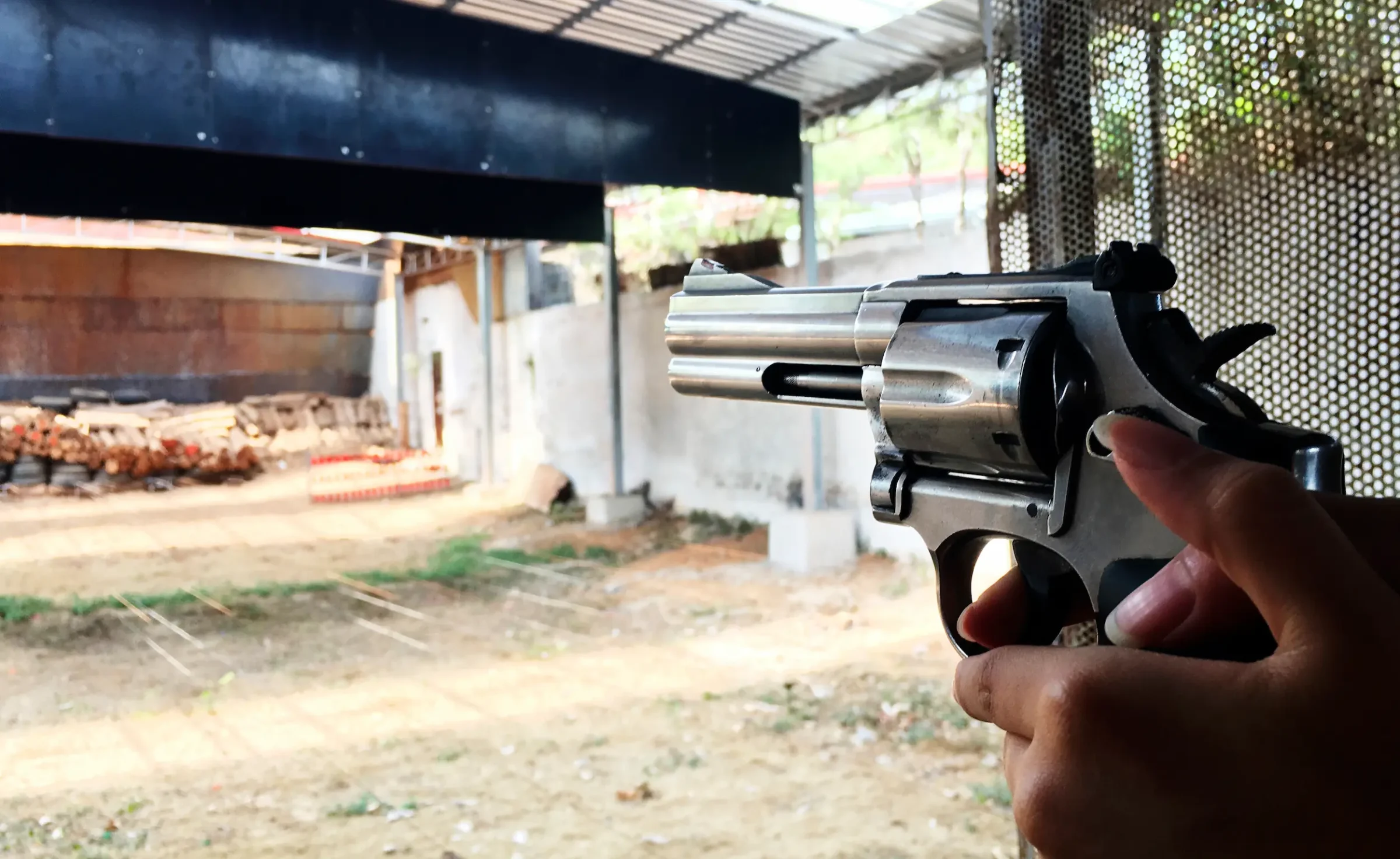 Pessoa segurando revólver em estande de tiro, ilustrando profissões com porte de arma autorizado no Brasil.